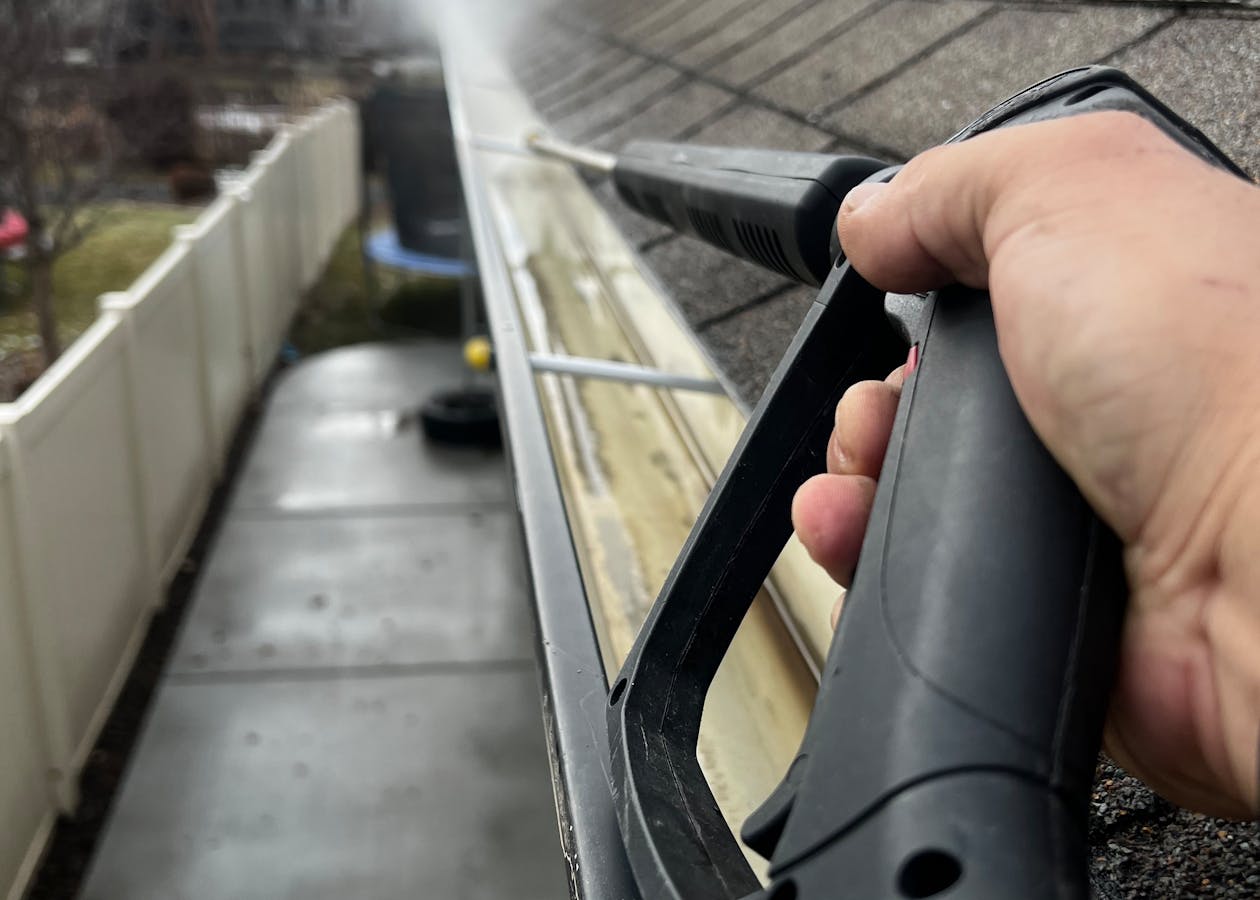 Residential gutter being cleaned with a pressure washer